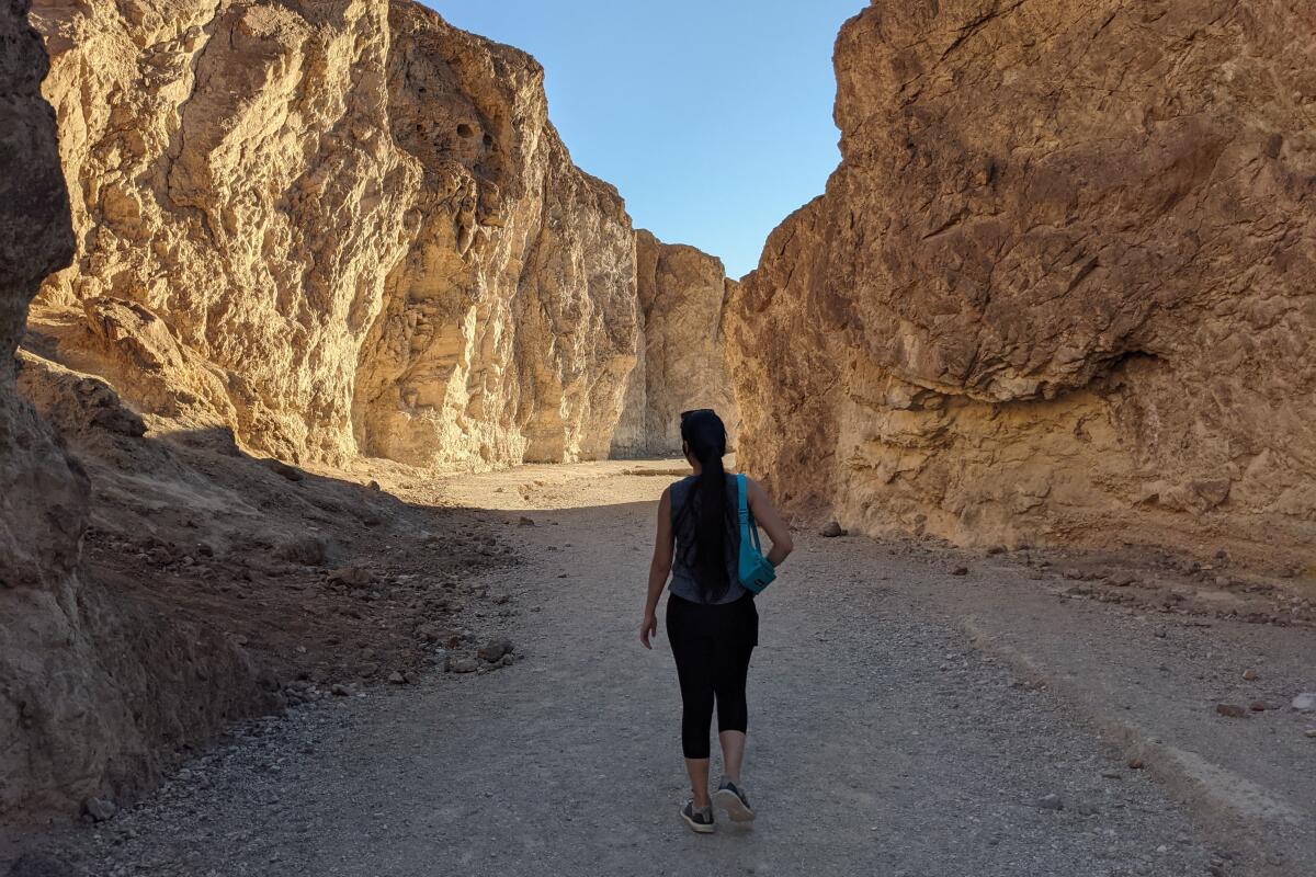 A woman walks between rocky cliffs.