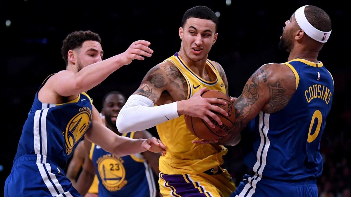 Kyle Kuzma is fouled by Golden State's DeMarcus Cousins as he drives past Klay Thompson during a game on Jan. 21 at Staples Center.