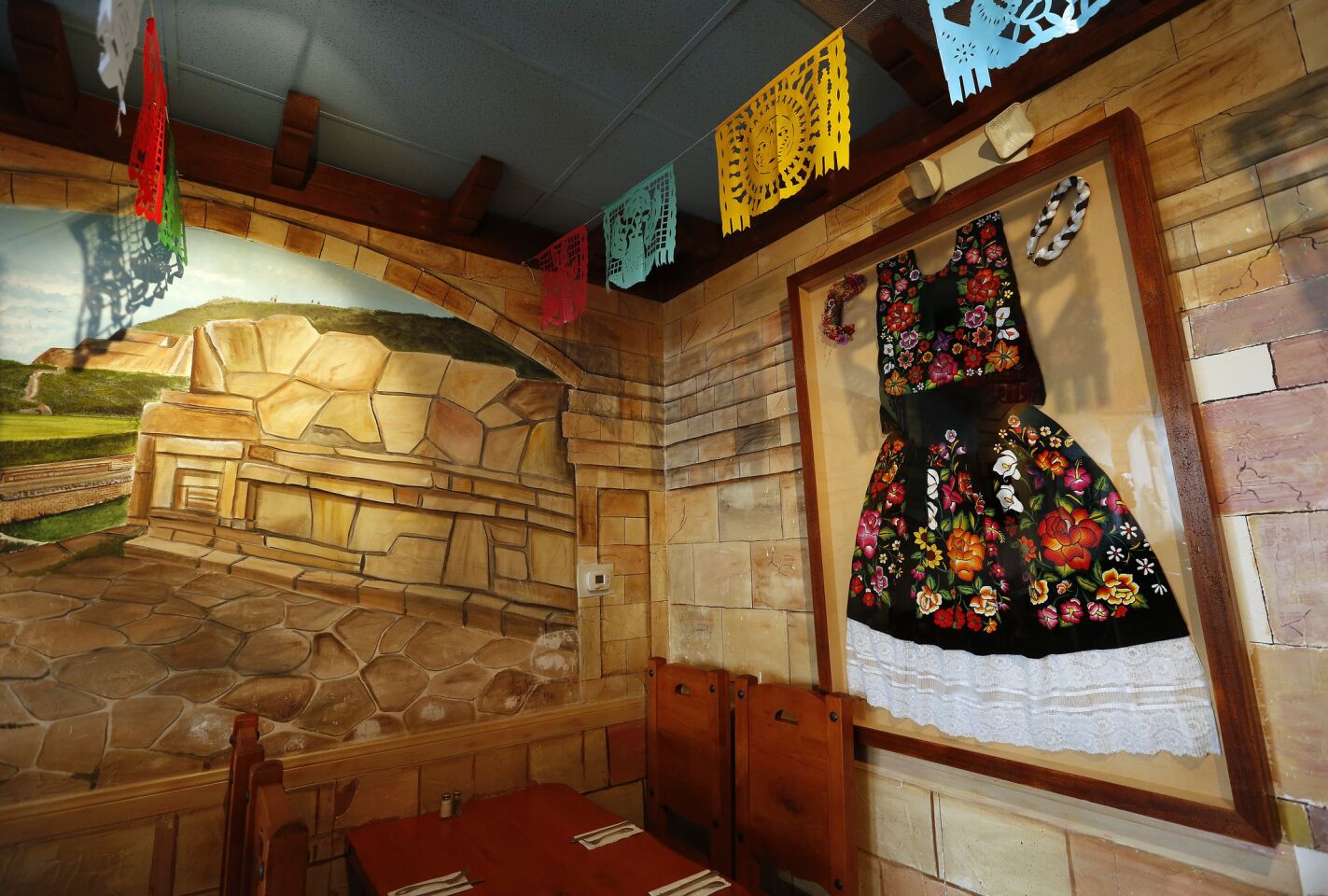 A flowered, lace-trimmed dress from Tehuantepec hangs at the back of Monte Alban, a Oaxacan restaurant in West Los Angeles where tlayudas are king.