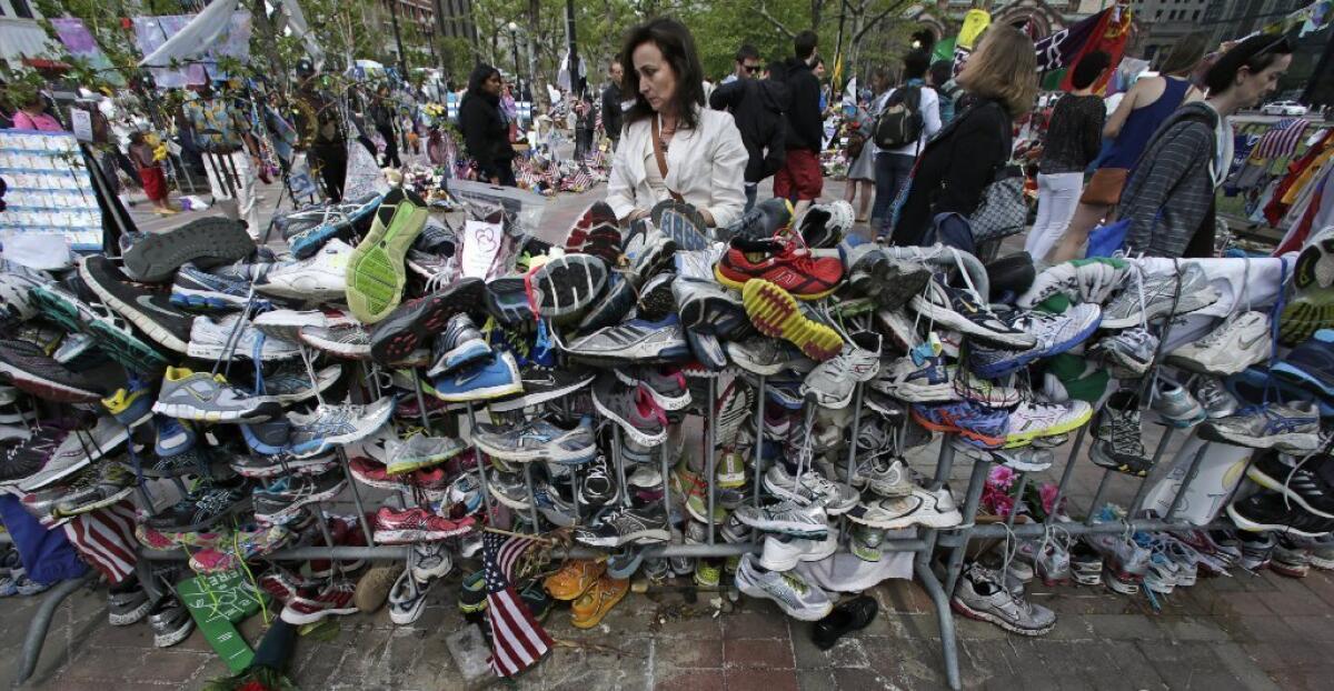 Notes are written on running shoes at the site of a memorial near the finish line of the Boston Marathon.