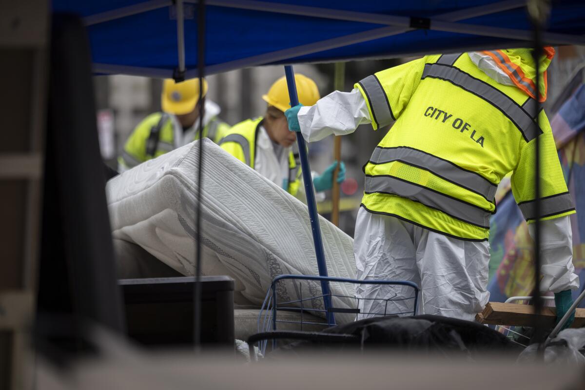 Los trabajadores de saneamiento de la ciudad toman un colchón durante la limpieza.