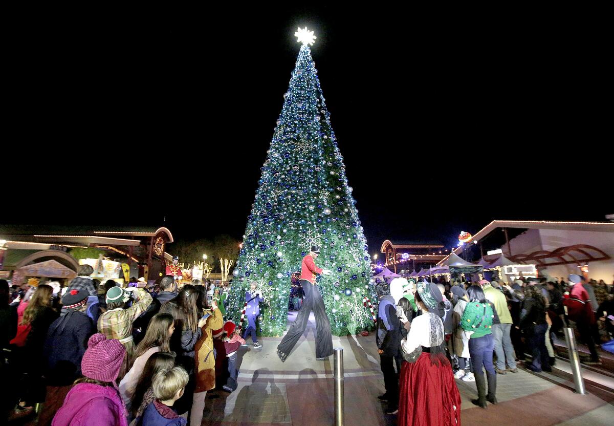 A nutcracker man on stilts walks around the Christmas tree during the Winter Fest OC celebration.