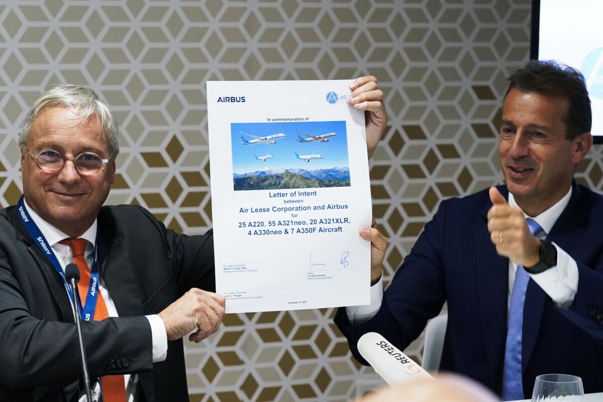 Airbus chief commercial officer Christian Scherer, left, and Airbus CEO Guillaume Faury react after signing a commemorative paper marking a deal at the Dubai Air Show in Dubai, United Arab Emirates, Monday, Nov. 15, 2021. Airbus announced Monday that it has received an order from the Air Lease Corporation for 111 new aircraft, its second blockbuster deal announcement in as many days at the biennial Dubai Air Show. (AP Photo/Jon Gambrell)