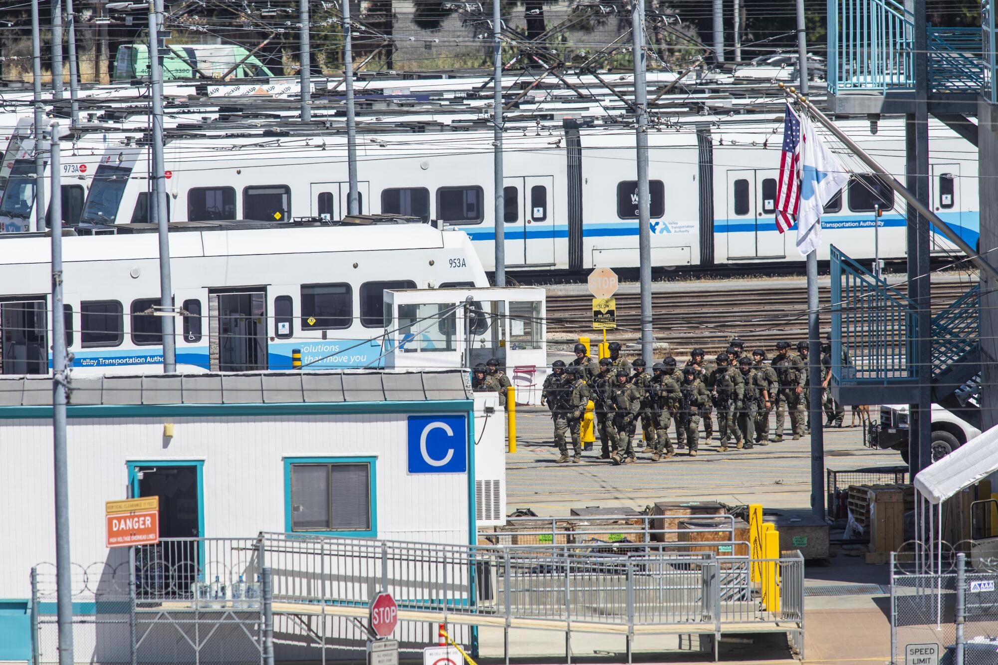 People in military uniforms walk through a rail yard.
