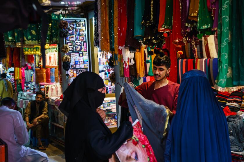 KABUL, AFGHANISTAN -- AUGUST 22, 2021: A shopkeeper shows his wares to the women shopoing in the womenOs area of the Lycee Maryam Bazaar in the Khair Khana neighborhood in Kabul, Afghanistan, Sunday, Aug. 22, 2021. (MARCUS YAM / LOS ANGELES TIMES)