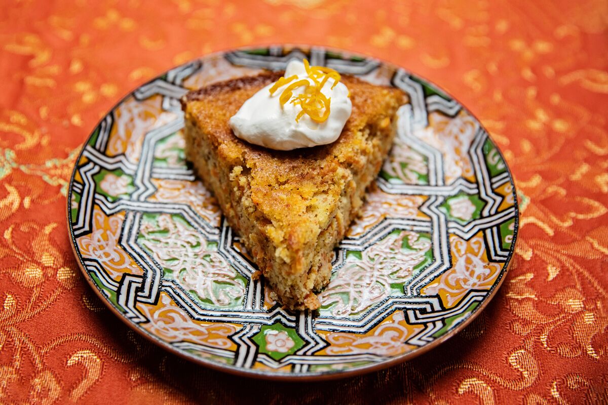 A slice of carrot cake, topped with whipped cream, on a plate.