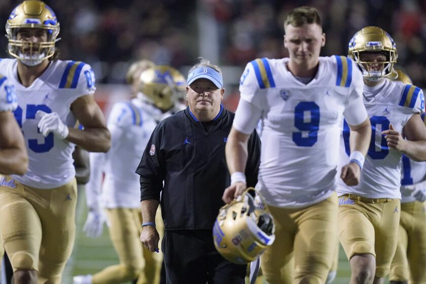 UCLA coach Chip Kelly runs off the field with the team at the end of the first half against Utah