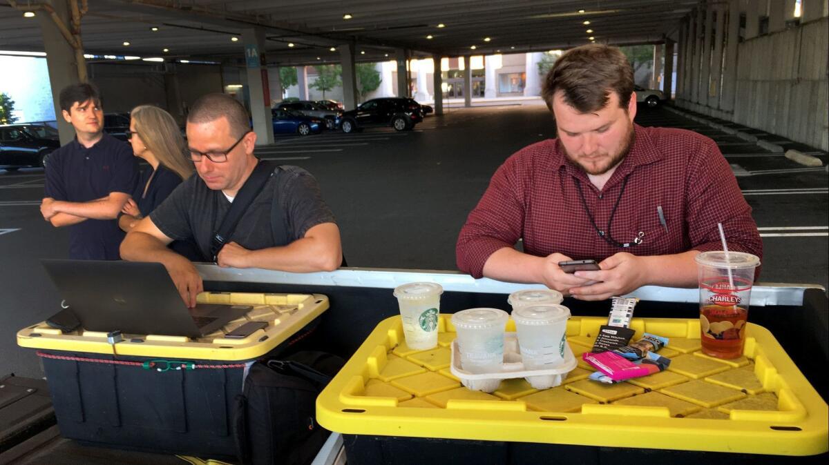 Photographer Joshua McKerrow, left, and reporter Chase Cook work on Friday's edition of the Capital from a parking lot after a shooting at the Annapolis, Md., newsroom that left five dead