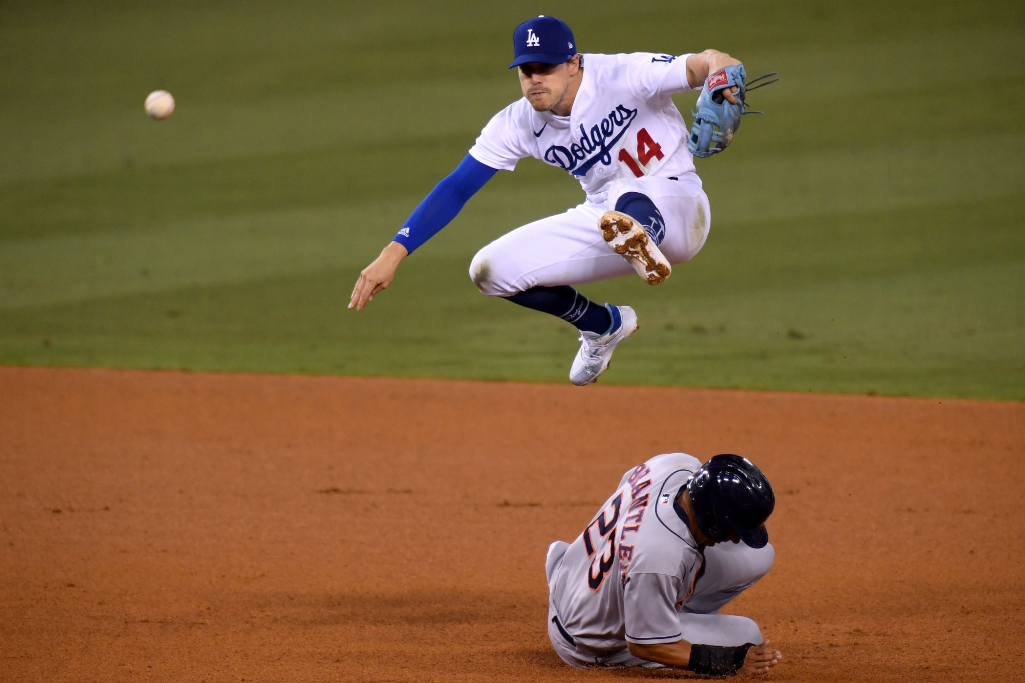 Dodgers' Kiké Hernández jumps over Astros' Michael Brantley on his throw to first base while trying to turn a double play.