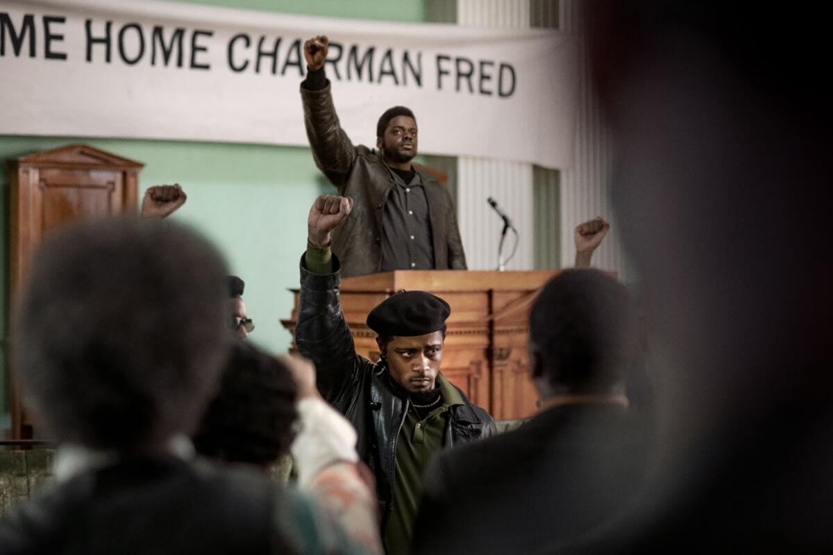 Daniel Kaluuya, at a podium, and LaKeith Stanfield stand with their right fists raised.