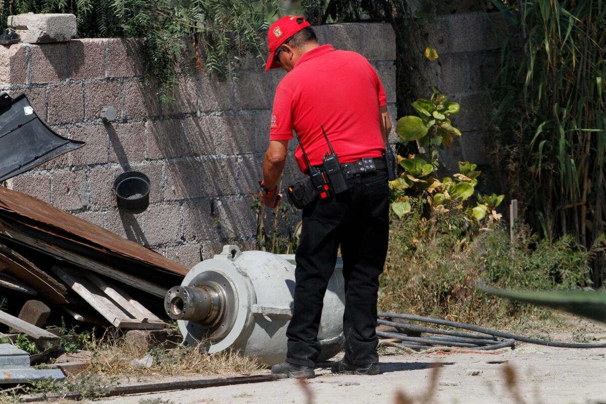 A firefighter takes photographs of radiation equipment on the patio of the family who found it in a nearby field outside Mexico City.