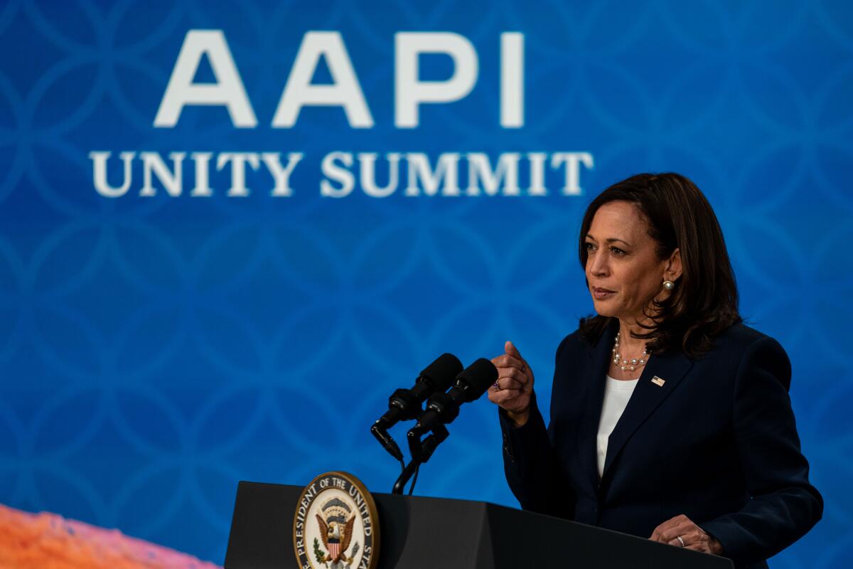 Kamala Harris stands in front of sign that reads "AAPI Unity Summit" 