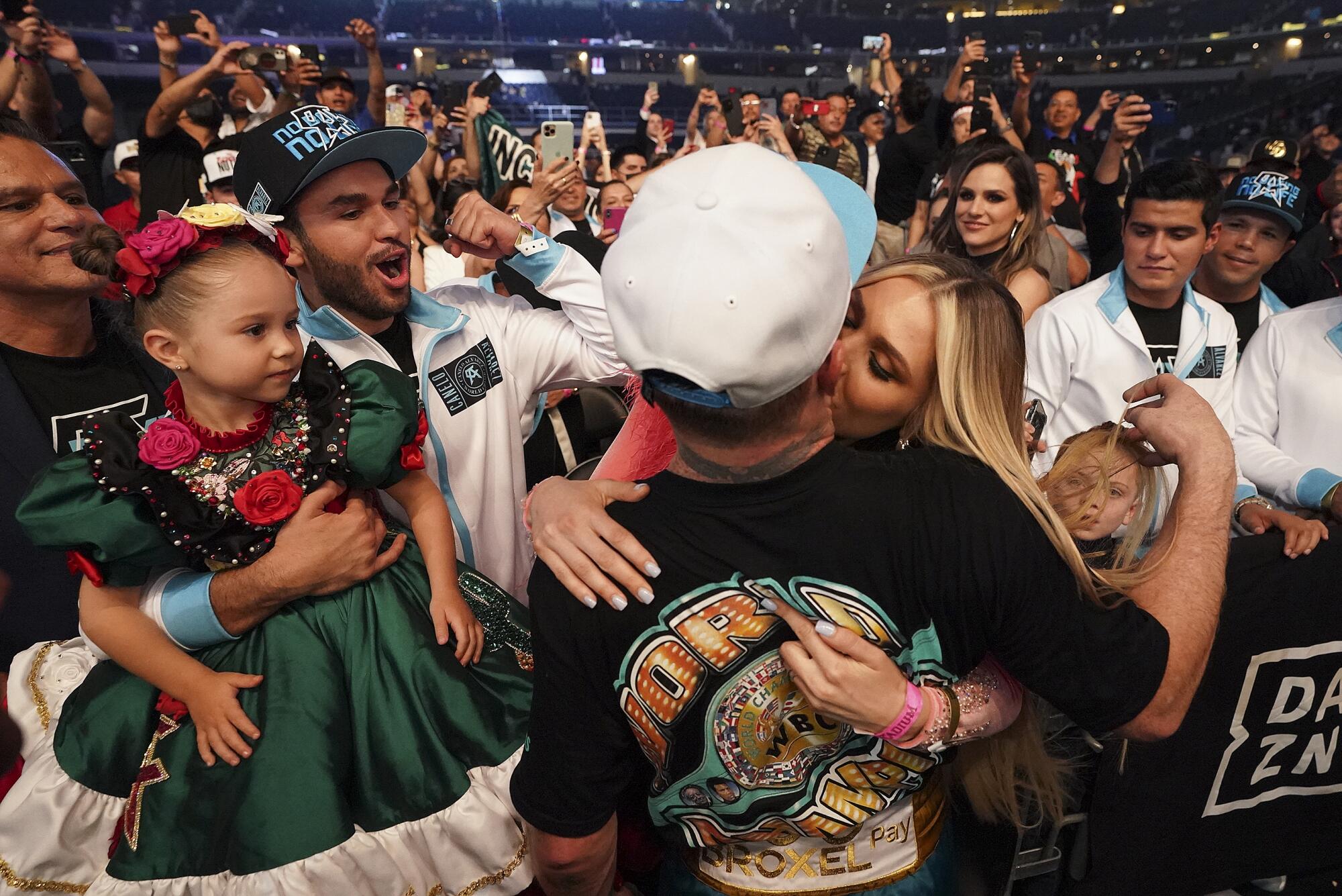 Canelo Álvarez kisses his girlfriend in the crowd as someone holds up a little girl with flowers in her hair