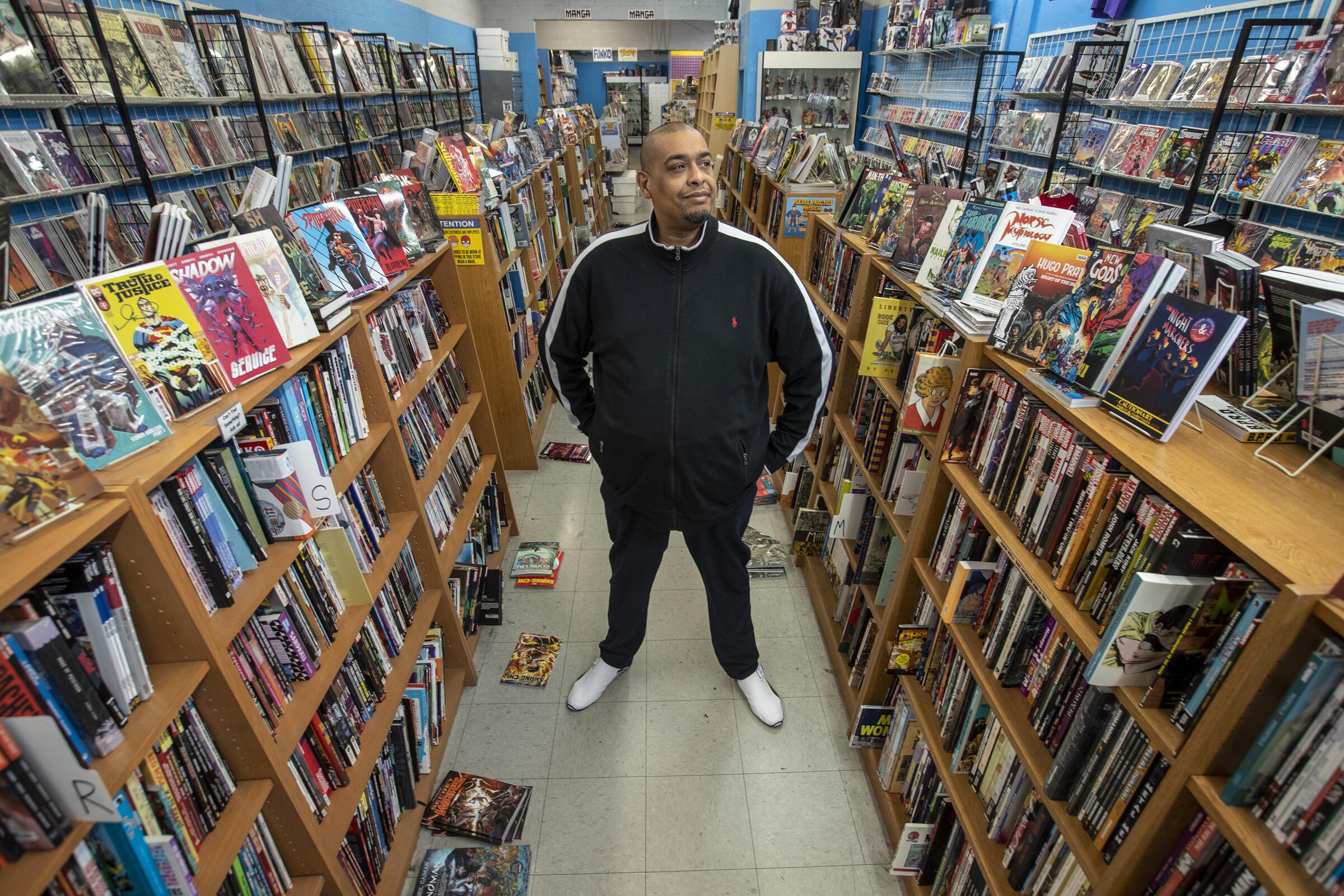 A man between shelves filled with graphic novels at a store.