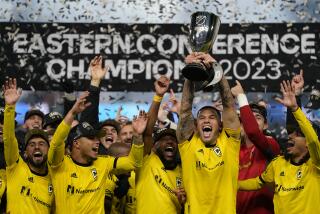Columbus Crew forward Christian Ramirez holds up a trophy as he celebrates with teammates 