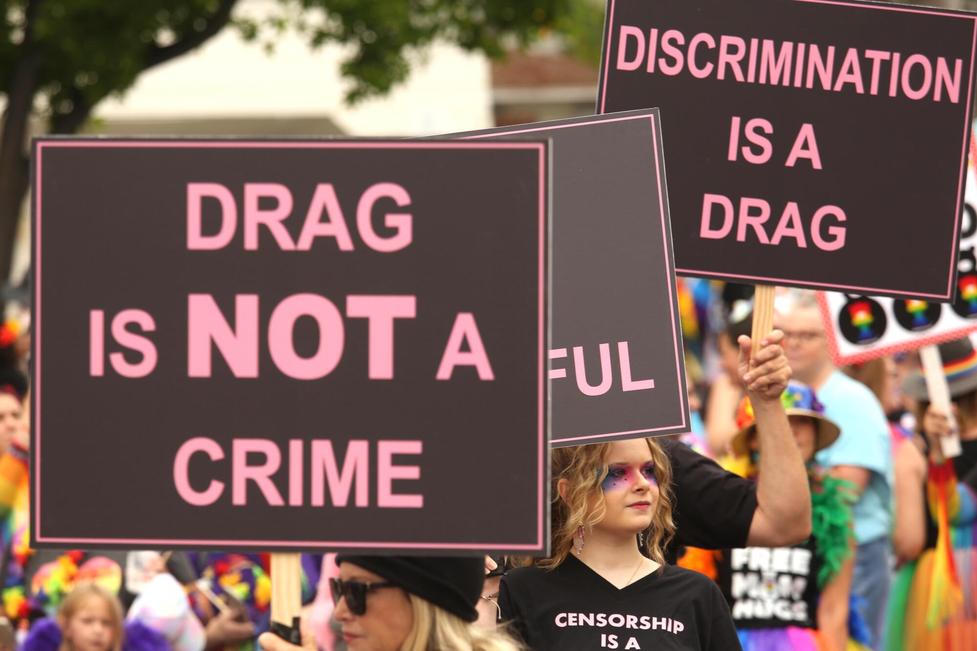 A person amid a crowd holds a sign that says "Drag is not a crime."