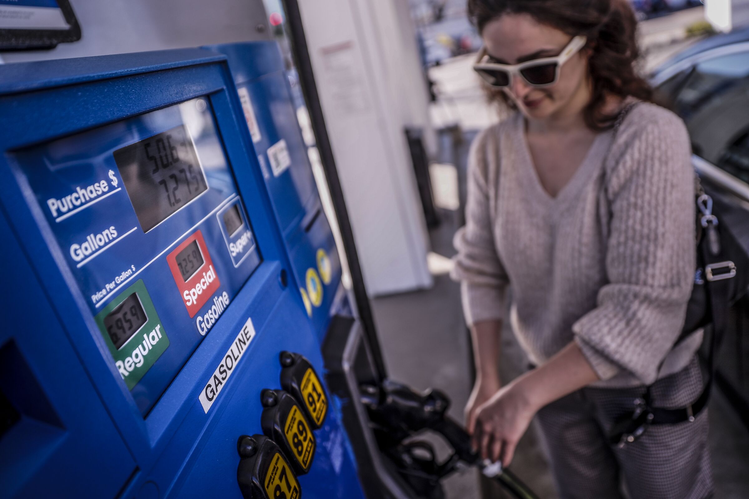 A customer pumps gas at $6.95 a gallon at a Mobil station