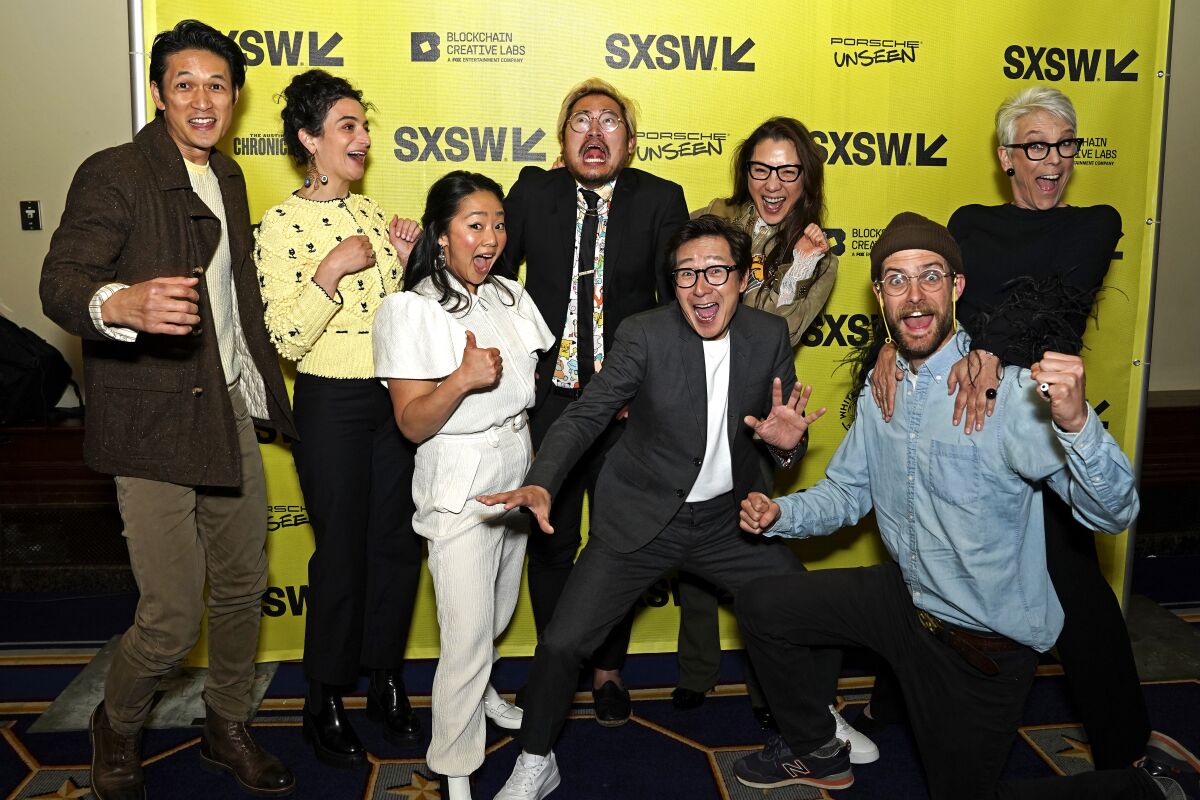 "Everything Everywhere All at Once" stars smile and strike funny poses in front of a SXSW banner 