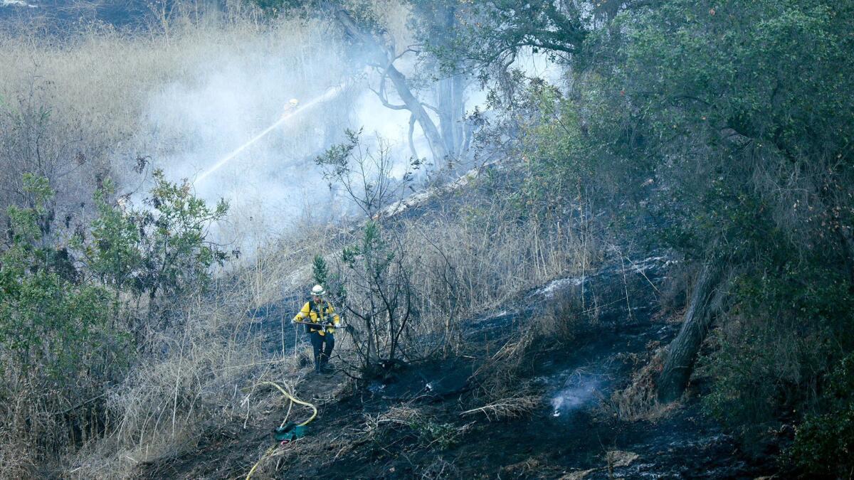 Firefighters mop up hot spots while battling two brush fires in the hills next to the 57 Freeway in Diamond Bar on Wednesday morning.