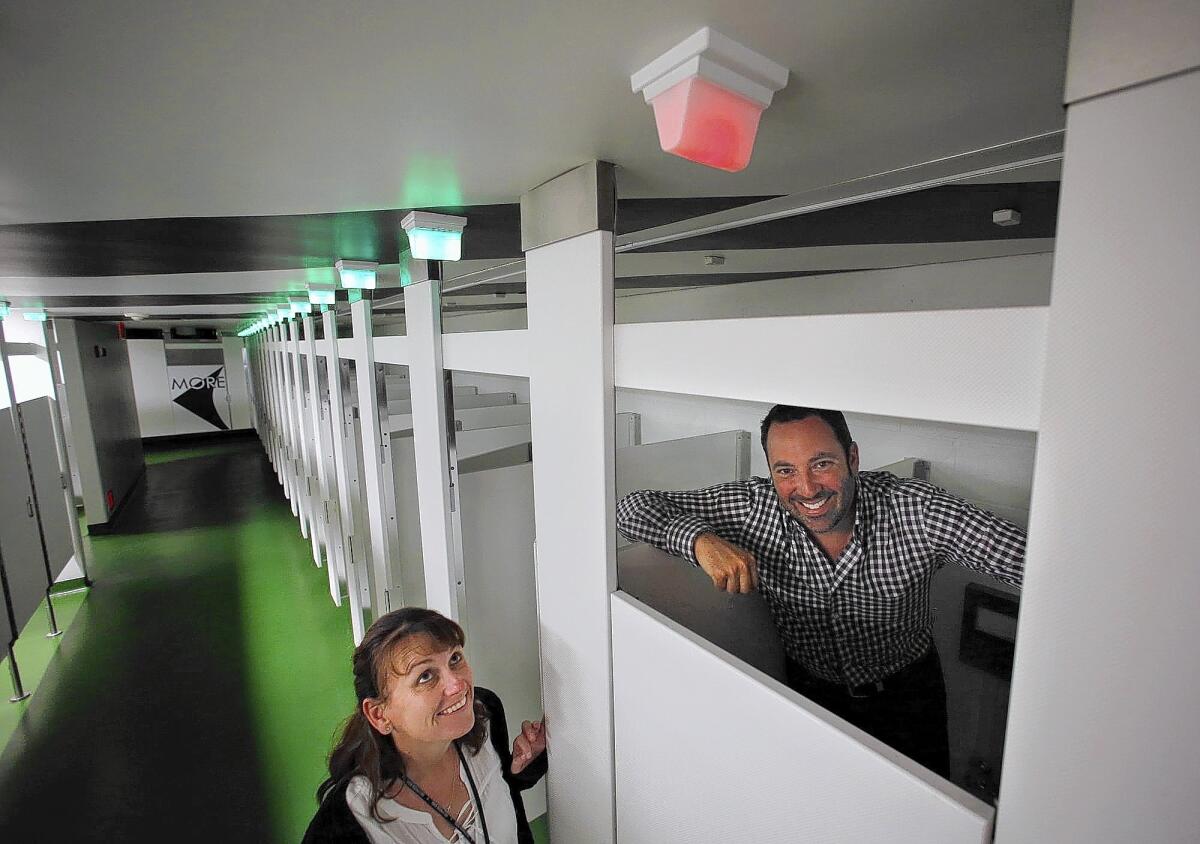 Chrissy Whitman, left, operations manager for the Hollywood Bowl, and Allen Klevens, co-founder of Tooshlights, show a lighting system designed by Klevens that lets female Bowl patrons know when restroom stalls are occupied or vacant.