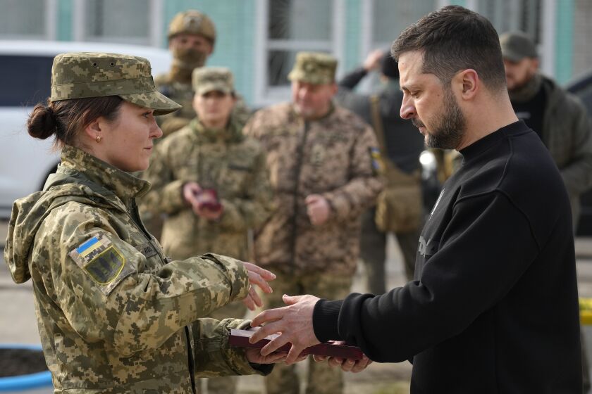Ukrainian President Volodymyr Zelenskyy presents a medal to a servicewoman in Okhtyrka in the Sumy region of Ukraine, Tuesday March 28, 2023. A team of journalists from The Associated Press traveled with Zelenskyy aboard his train for two nights as he visited troops along the front lines and communities that have been liberated from Russian control. Zelenskyy is hoping his trips keep the public's attention on the war, particularly in parts of Ukraine where life can often appear to have returned to normal. (AP Photo/Efrem Lukatsky)