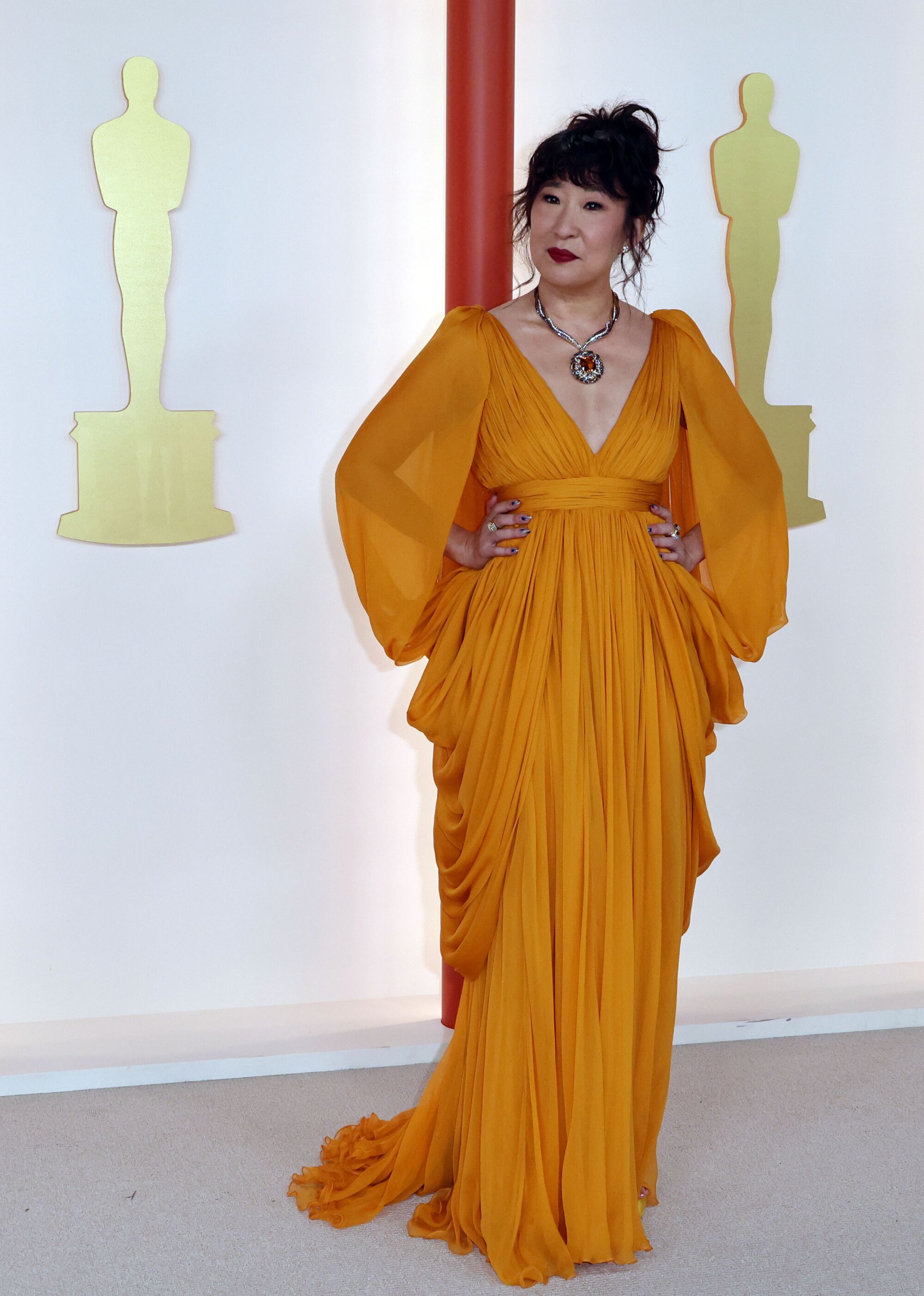 Sandra Oh in a marigold gown with fabric draped from the waist.