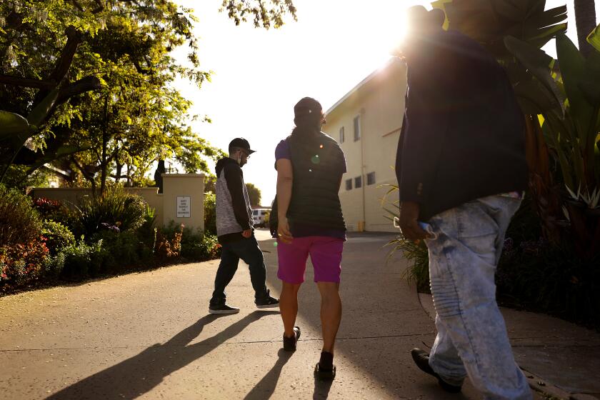 Mary Liciaga, center, and her friend Jeremiah Boseman, right, escort Anthony Mazzucca, 30, at left, back to Meadowbrook Behavioral Health Center where he currently resides, on Tuesday, April 5, 2022. (Christina House / Los Angeles Times)