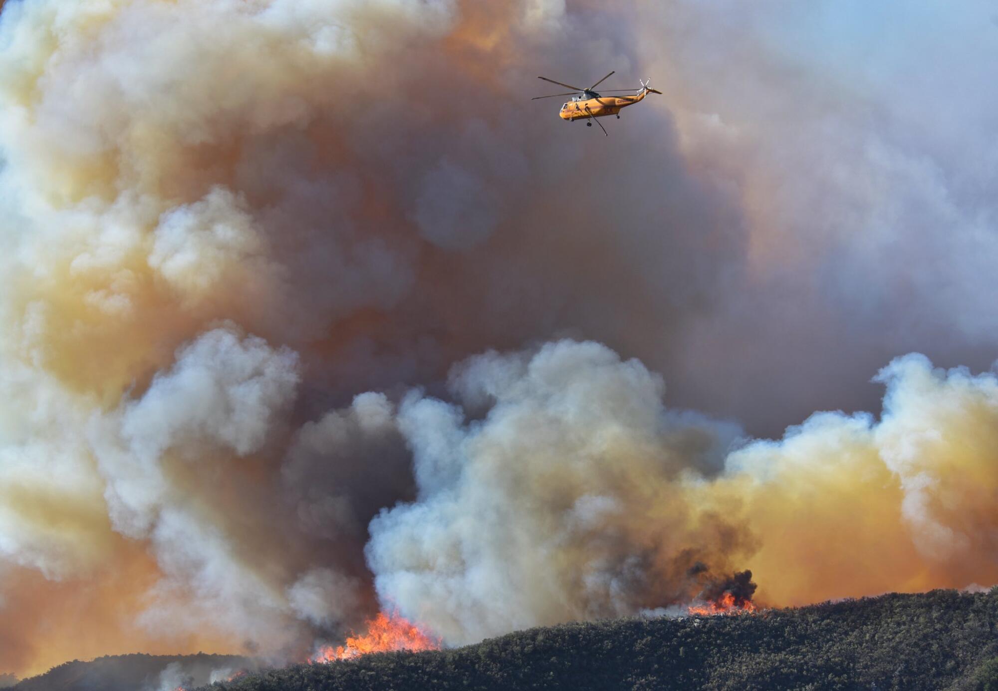 A helicopter flies through smoke.