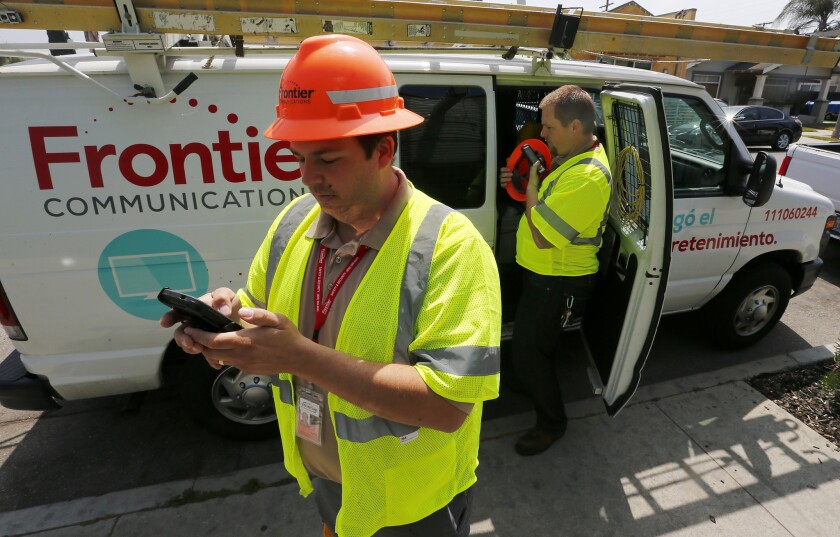 Frontier Communications technicians Airik Morales, left, and Jason Raine make a service call on Thursday at a restaurant in Long Beach that was not able to receive customer calls. Frontier has been trying to resolve internet and phone service issues since taking over Verizon FiOS customer homes and businesses on April 1.