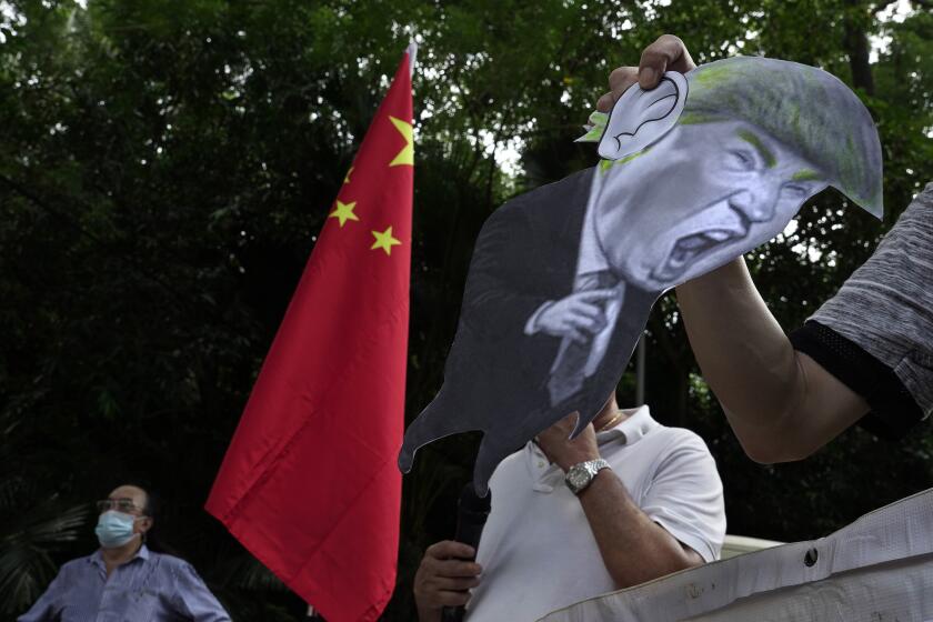 FILE - In this Aug. 8, 2020, file photo, pro-China supporters display a picture of U.S. President Donald Trump during a protest against the U.S. sanctions outside the U.S. Consulate in Hong Kong. China has announced Monday, Aug. 10, 2020, unspecified sanctions against 11 U.S. politicians and heads of organizations promoting democratic causes, including Senators Marco Rubio and Ted Cruz, who have already been singled out by Beijing. (AP Photo/Vincent Yu, File)