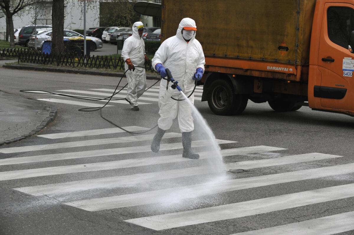 Municipal workers wearing protective clothing spray disinfectant on the streets to prevent the spread of the coronavirus in Budapest, Hungary.