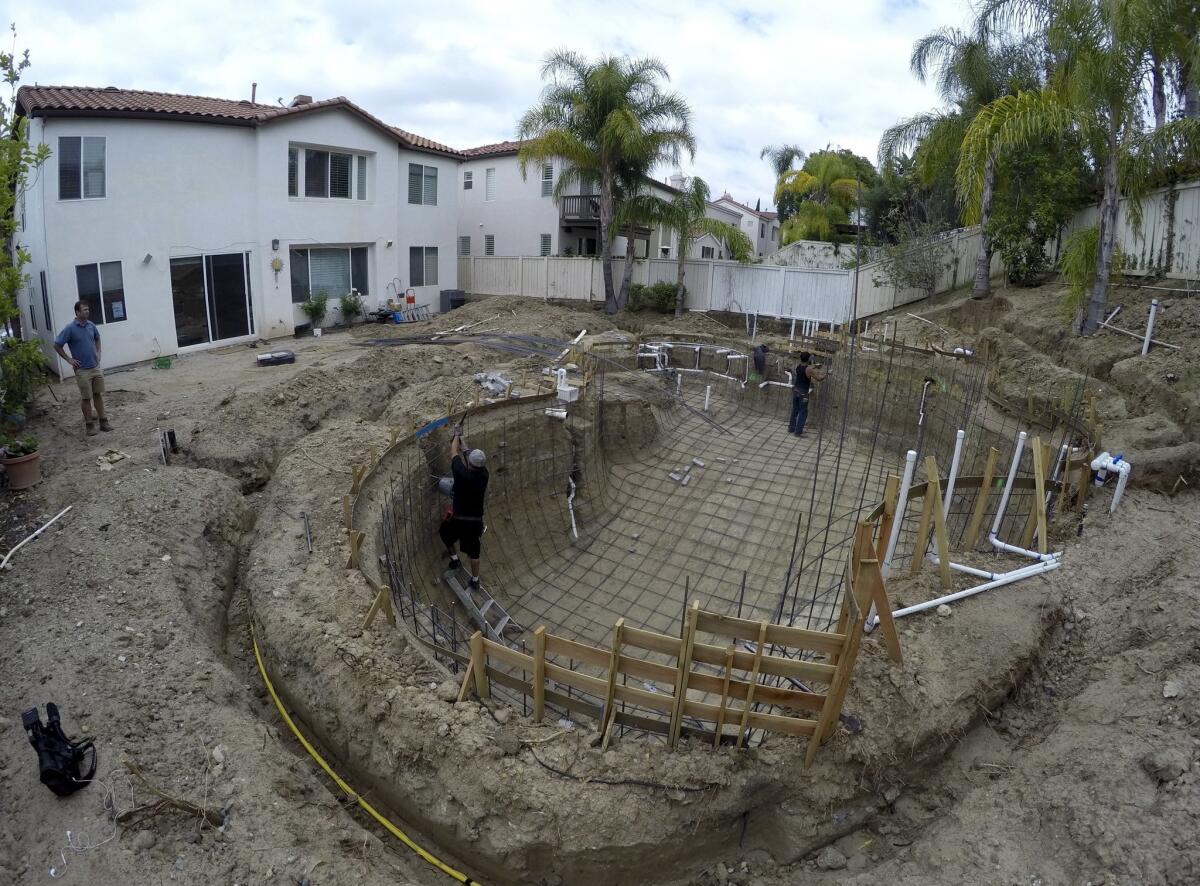 Just a tad too late? A construction crew digs a new pool in Tustin, just as communities across California ponder whether to forbid the filling of new pools.