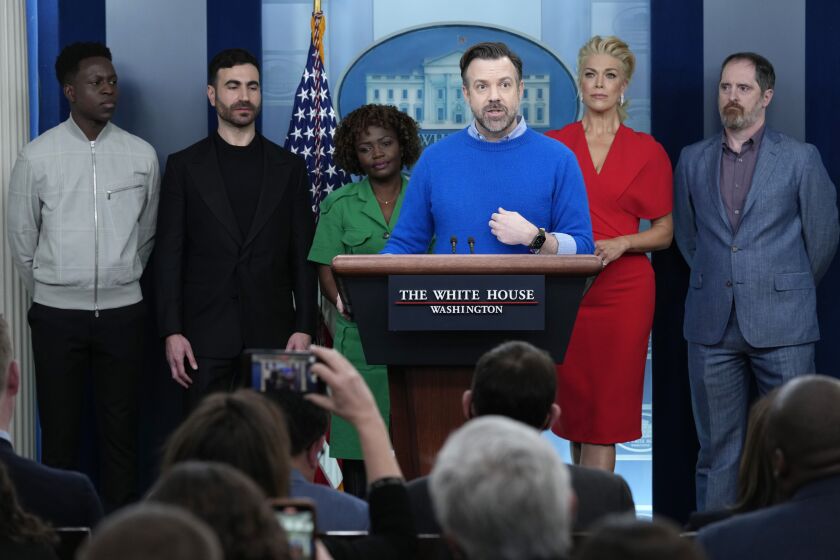 Jason Sudeikis, fourth from left, who plays the title character in the Apple TV+ series “Ted Lasso”, speaks as he joins White House press secretary Karine Jean-Pierre, third from left, and fellow cast members, from left, Toheeb Jimoh, Brett Goldstein, Hannah Waddingham, and Brendan Hunt, during the daily press briefing at the White House in Washington, Monday, March 20, 2023. (AP Photo/Susan Walsh)