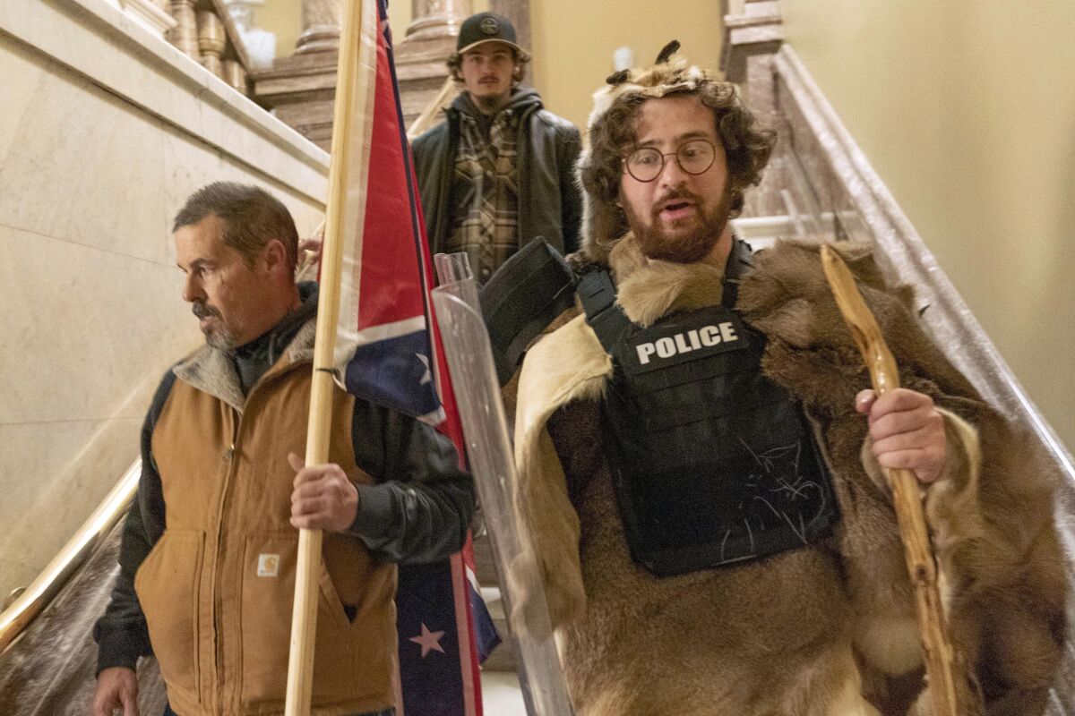 FILE — Supporters of President Donald Trump, including Aaron Mostofsky, right, who is identified in his arrest warrant, walk down the stairs outside the Senate Chamber in the U.S. Capitol, in Washington, Jan. 6, 2021. Mostofsky, the son of a New York judge, who referred to himself as a "caveman" eager to protest Donald Trump's presidential election loss, was sentenced on Friday, May 6, 2022, to eight months in prison. U.S. District Judge James Boasberg told Mostofsky that he was "literally on the front lines” of the mob's attack on Jan. 6, 2021. (AP Photo/Manuel Balce Ceneta, File)
