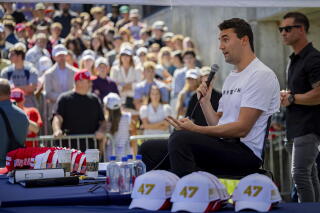 A man speaks into a microphone as a crowd watches.
