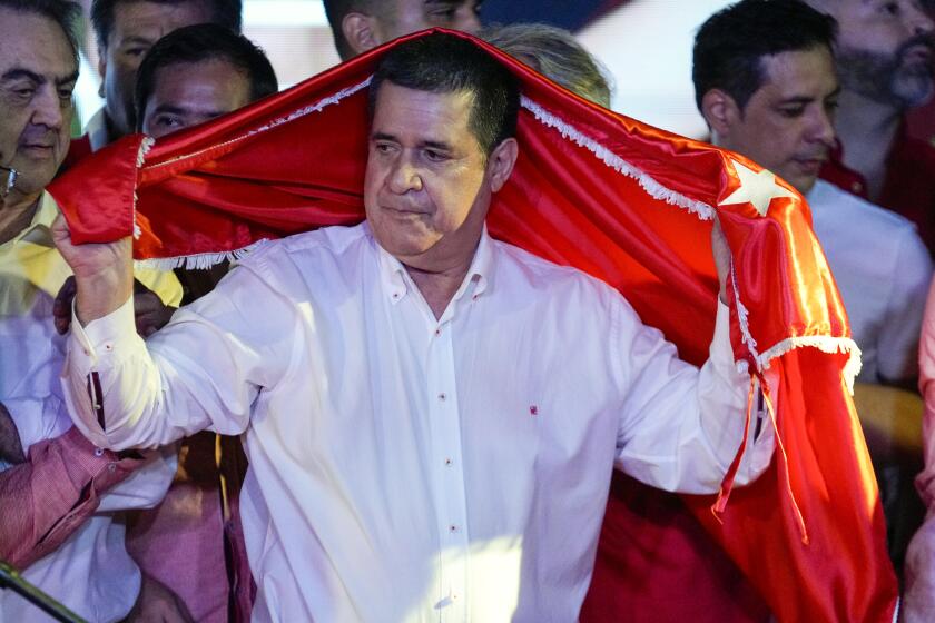 ARCHIVO - El expresidente Horacio Cartes se cubre con una bandera del gobernante Partido Colorado después del cierre de las urnas durante las elecciones generales en Asunción, Paraguay, el 30 de abril de 2023. El gobierno de Estados Unidos sancionó el martes 6 de agosto de 2024 a una compañía tabacalera de Paraguay que habría suministrado apoyo financiero a Cartes, a quien Washington incluyó en una lista de personas corruptas hace más de un año. (AP Foto/Jorge Saenz, Archivo)