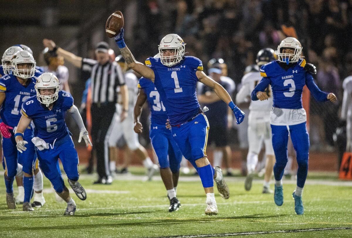 Fountain Valley's Fernando Garcia raises the ball in celebration after intercepting a pass during a game against Marina.