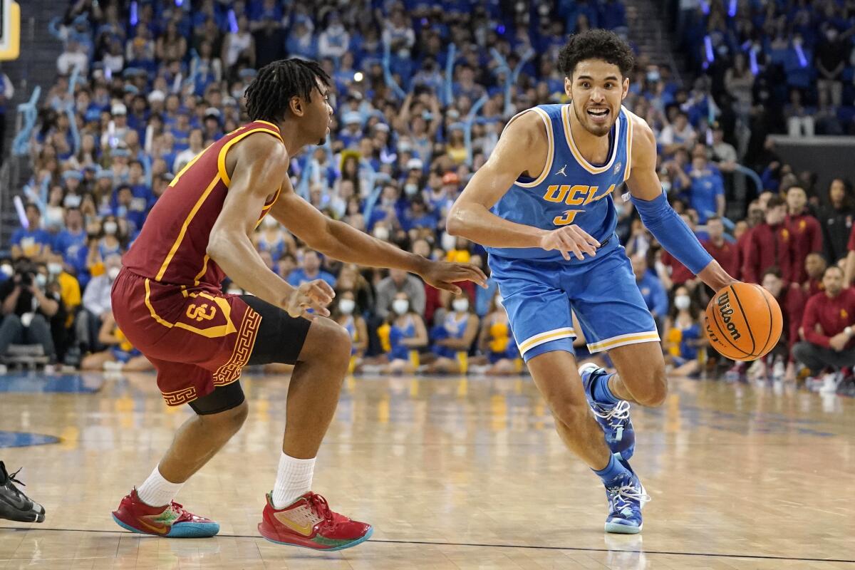 UCLA guard Johnny Juzang, right, drives by USC guard Reese Dixon-Waters