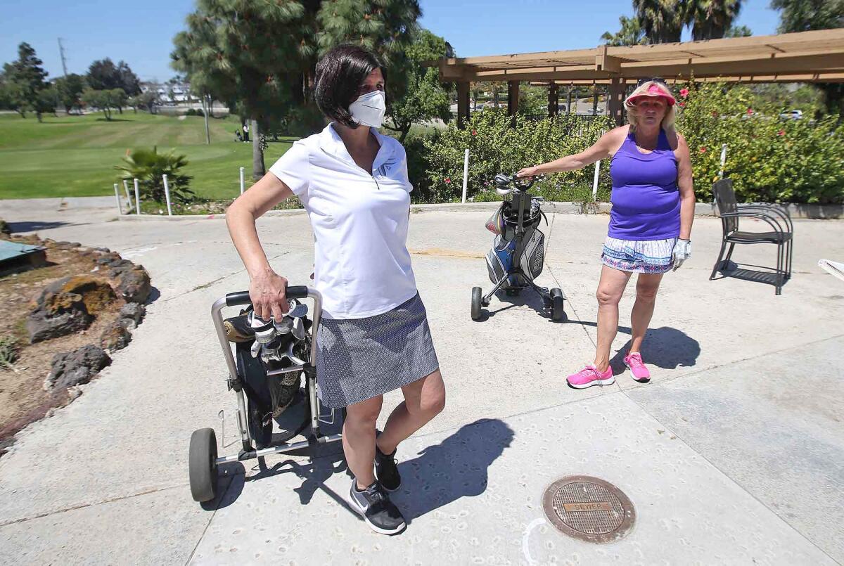 Friends and longtime patrons of Newport Beach Golf Course, Mira Winters and Marilee Johnson, from left, walk off after a round on Friday.