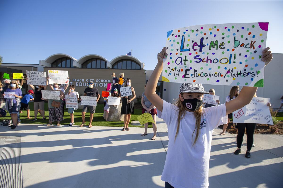 Elliana Emerson, 12, holds a sign during a rally at the Huntington Beach City School District on Tuesday.