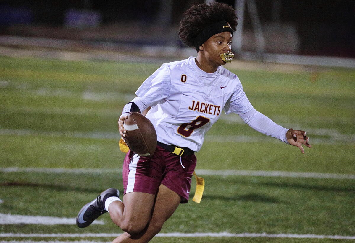 Oxnard quarterback Ryanna Harris runs with the football while looking across the field.
