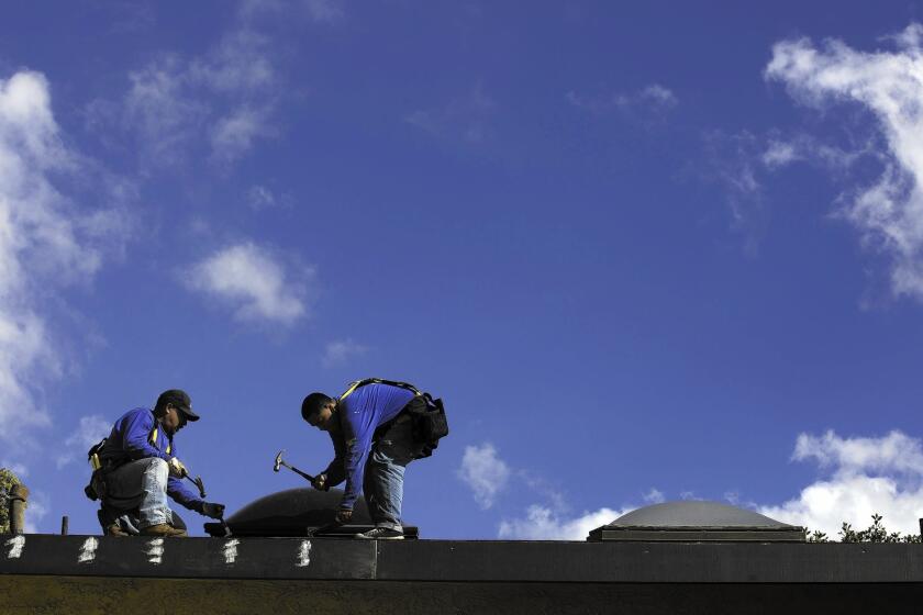 The National Weather Service has predicted that the area from San Diego to Los Angeles has a 60% to 69% chance of “above normal precipitation” this winter because of the El Niño weather phenomenon. Above, roofers at a condo complex in Lakewood.