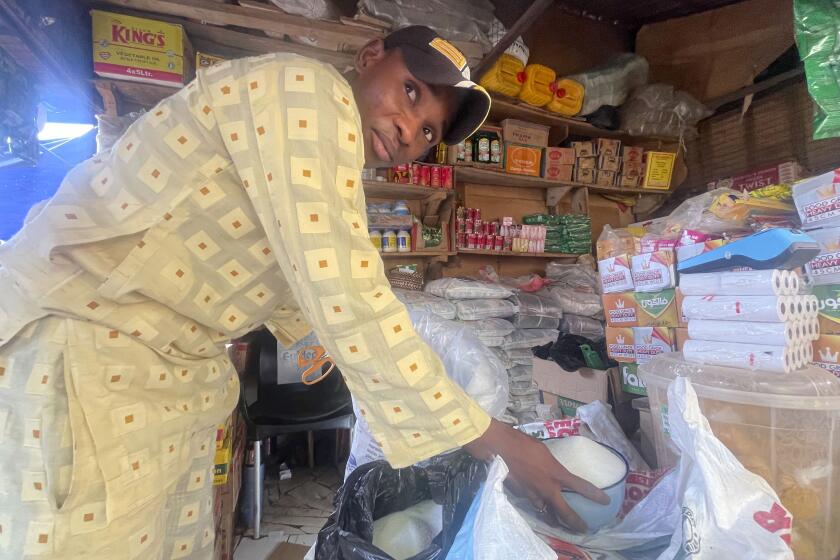 Abba Usman sells granulated sugar at his shop inside a market in Abuja, Nigeria, Friday, Oct. 27, 2023. The same 50-kilogram (110-pound) bag of sugar that Usman bought a week ago for $66 now costs $81. As prices rise, his customers are dwindling. (AP Photo/Chinedu Asadu)