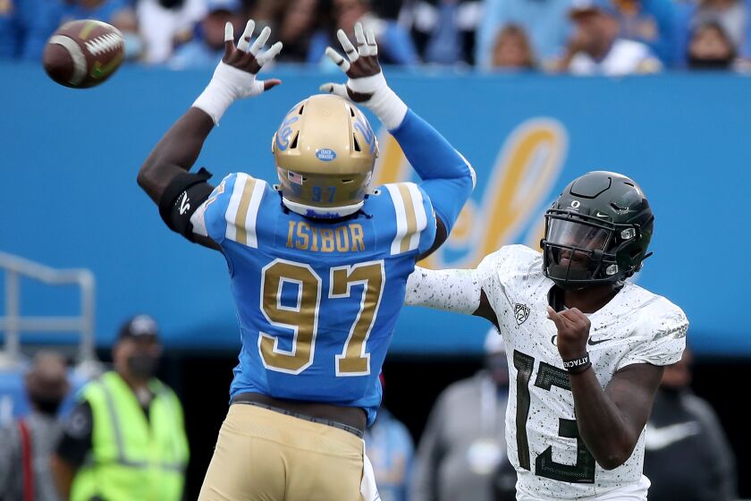 PASADENA, CALIF. - OCT. 23, 2021. Oregon quarterback Anthony Brown gets pressure from UCLA defensive lineman Odua Isibor in the first quarter at the Rose Bowl in Pasadena on Saturday, Oct. 23, 2021. . (Luis Sinco / Los Angeles Times)