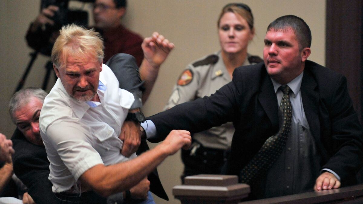 Wesley Thomas, the step father of Tiffany York, is tackled by courtroom security during the hearing of defendant Sgt. Anthony Peden at Long County Superior Court, Thursday Aug. 30, 2012, in Ludowici, Ga. District Attorney Tom Durden announced in court that he will seek the death penalty for Peden, Pvt. Isaac Aguigui, and Pvt. Christopher Salmon. The three Fort Stewart soldiers are accused of malice murder, felony murder and criminal gang activity in the Dec. 4 slayings of former soldier Michael Roark and his girlfriend, 17yearold Tiffany York. The two were found shot to death off a dirt road near the Army post. Prosecutors say the accused men were part of a militia operating within the U.S. Army that was stockpiling weapons and wanted to overthrow the federal government. (AP Photo/Stephen Morton)