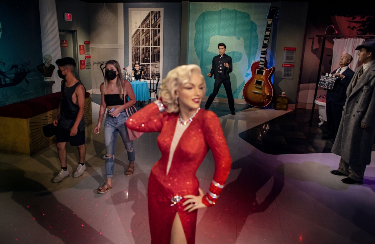 Tourists walk near wax figures of Elvis Presley and Marilyn Monroe at Madame Tussauds.