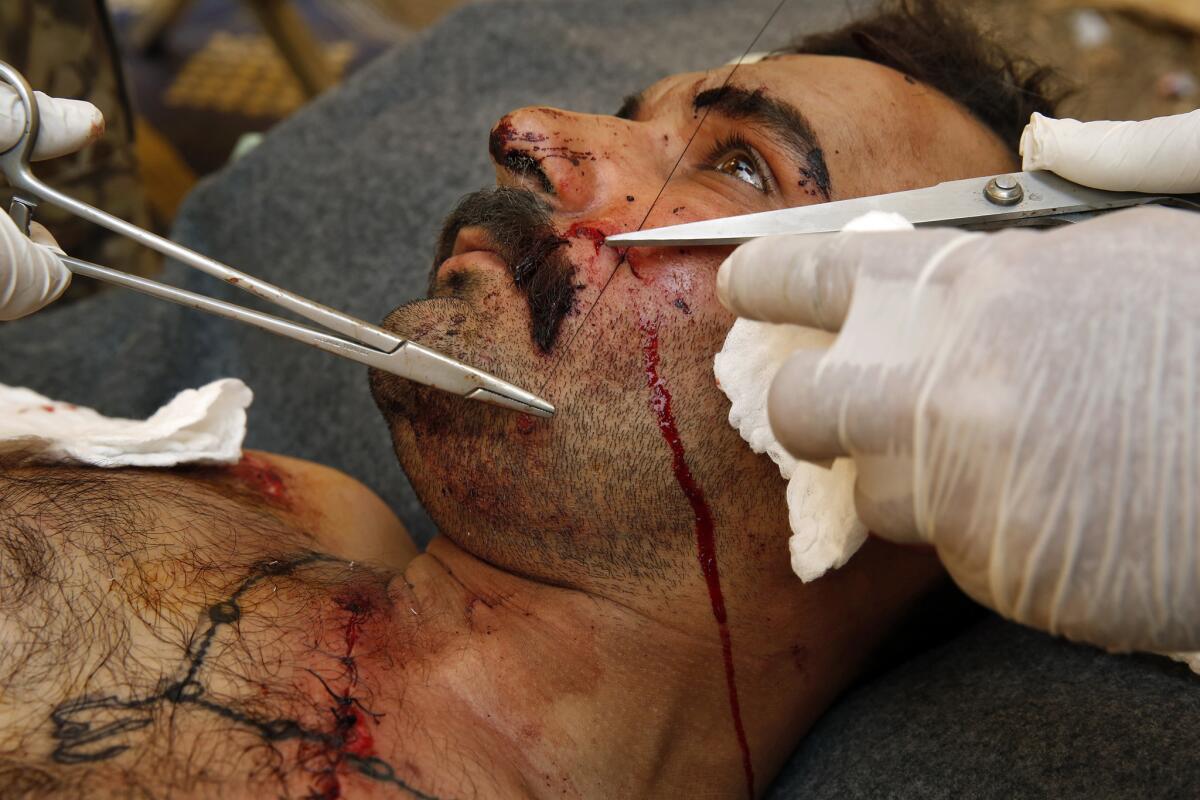 Maj. Gen. Raad Mohssan Dakhel stitches up a soldier's face after he was injured by a suicide bomb explosion.