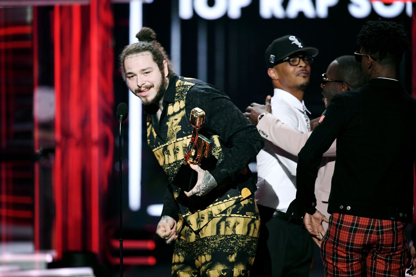 Recording artist Post Malone accepts the top rap song award for "Rockstar" from rapper T.I. onstage during the 2018 Billboard Music Awards.