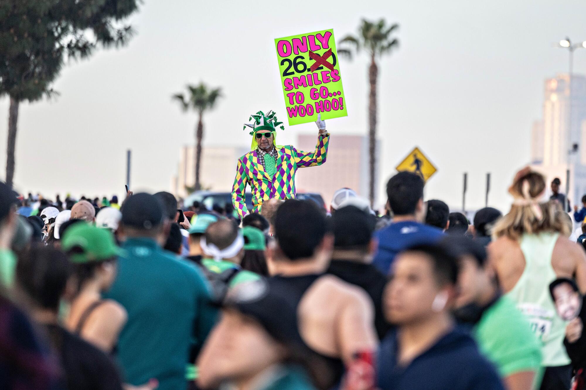 A man holds a sign reading "Only 26.2 Smiles To Go" at the L.A. Marathon.