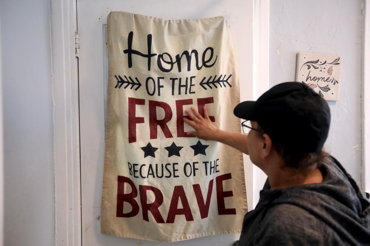 A woman touches a banner she's hung in her home in El Sereno.